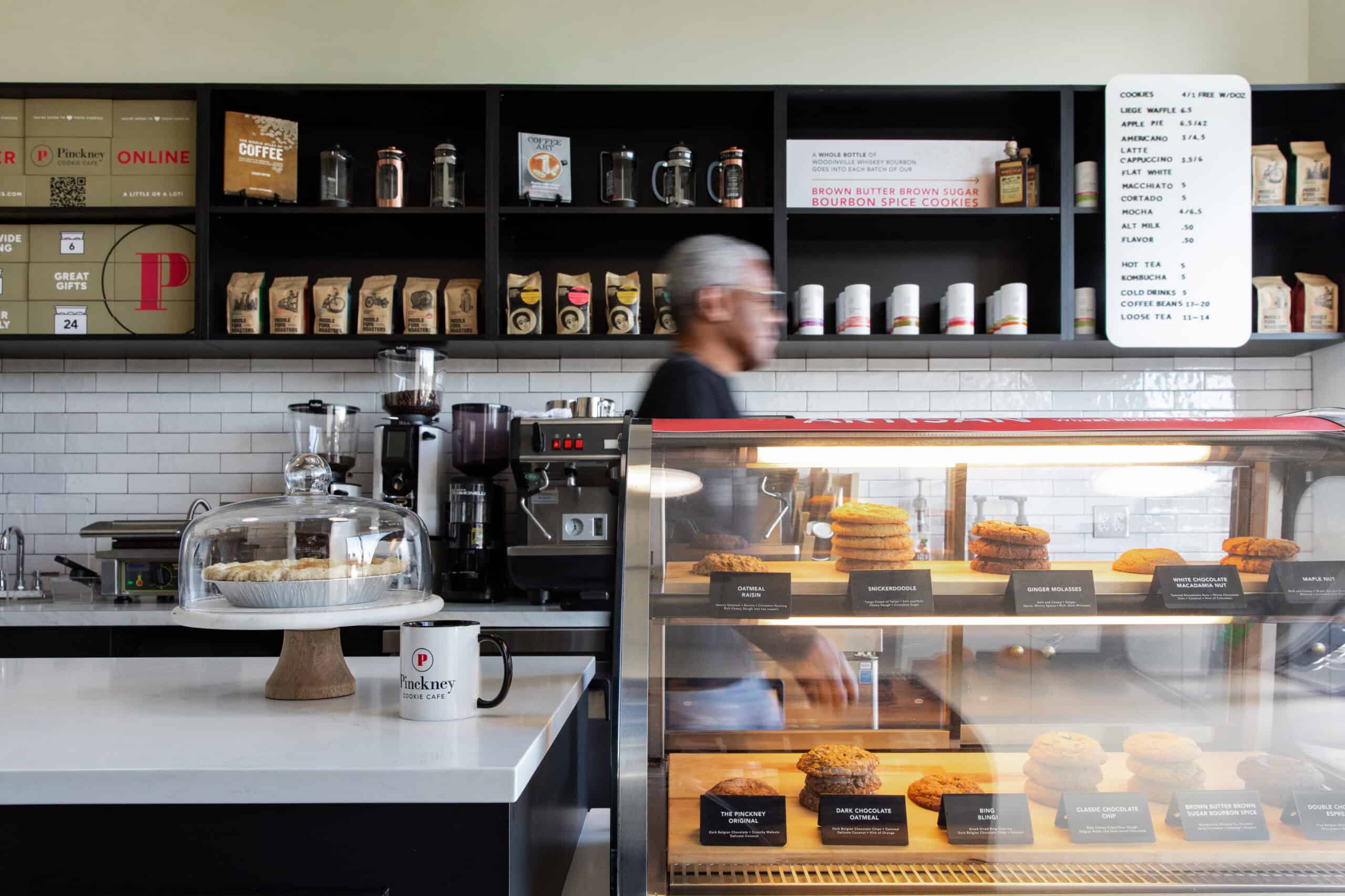 Modern coffee shop interior with display case and barista at work.