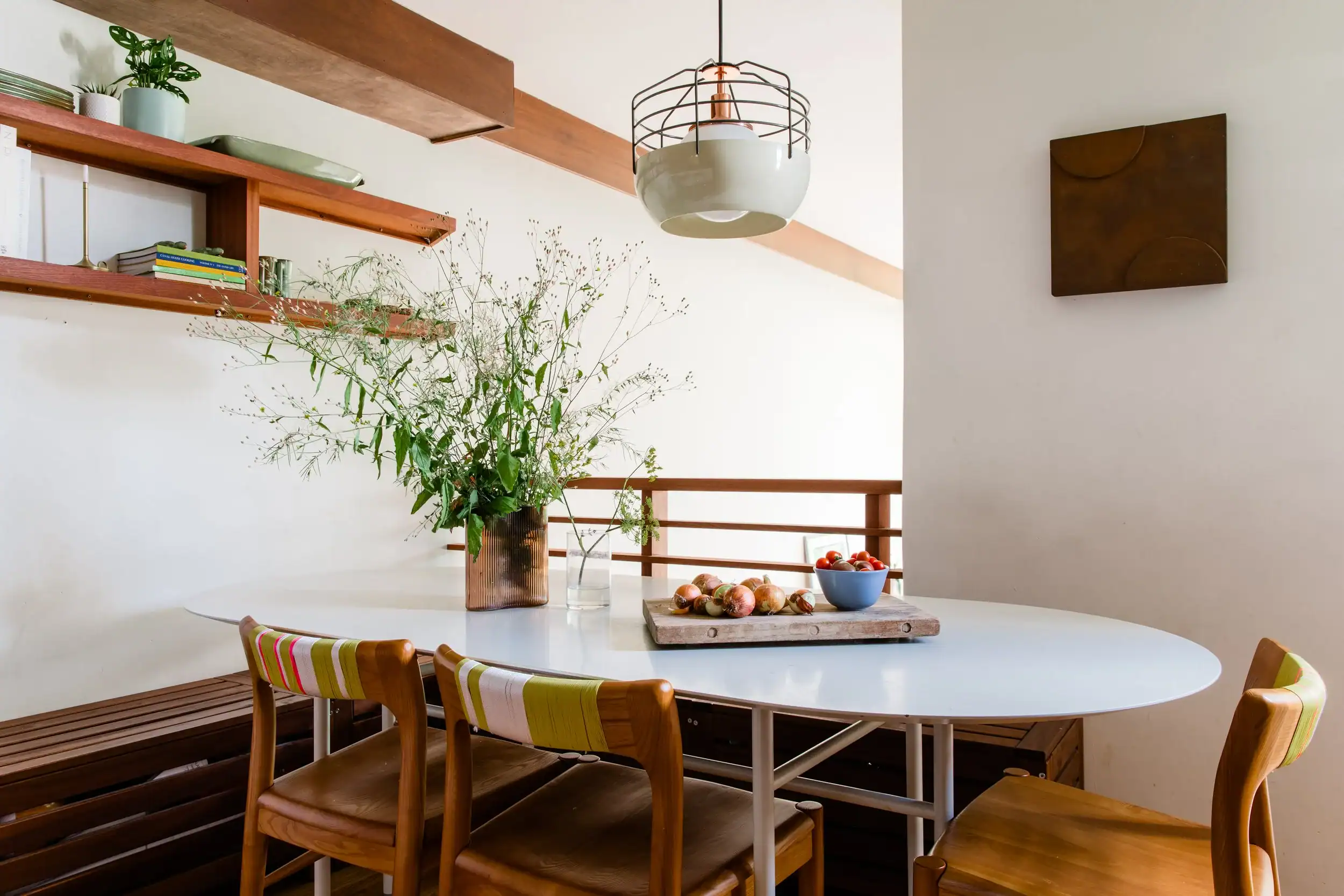 Modern dining space with round table, wooden chairs, and minimalist decor.