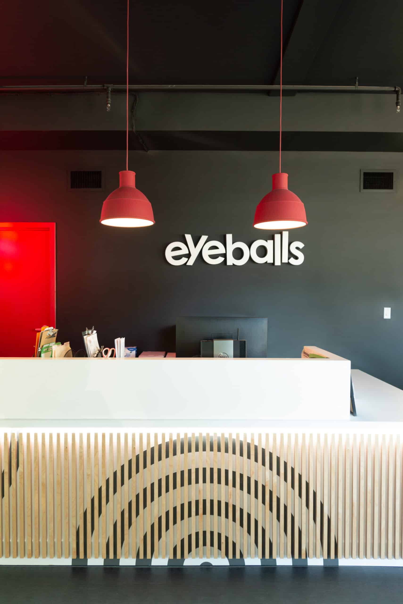 Modern office reception with Eyeballs sign and red pendant lights.