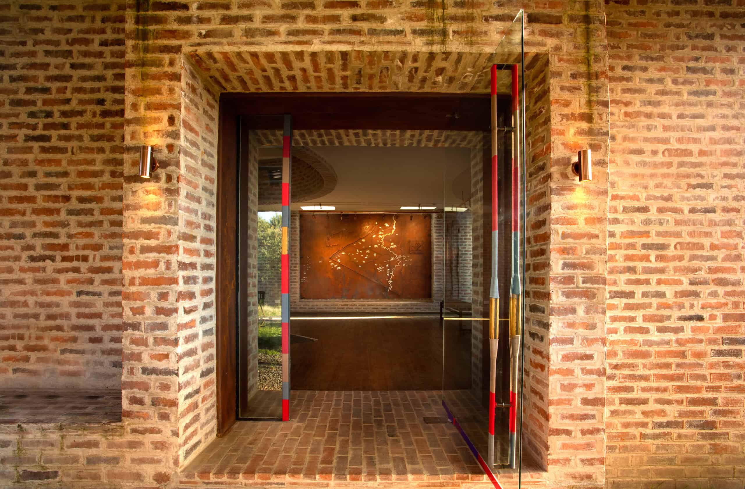 Modern brick building entrance with glass door and ambient lighting.