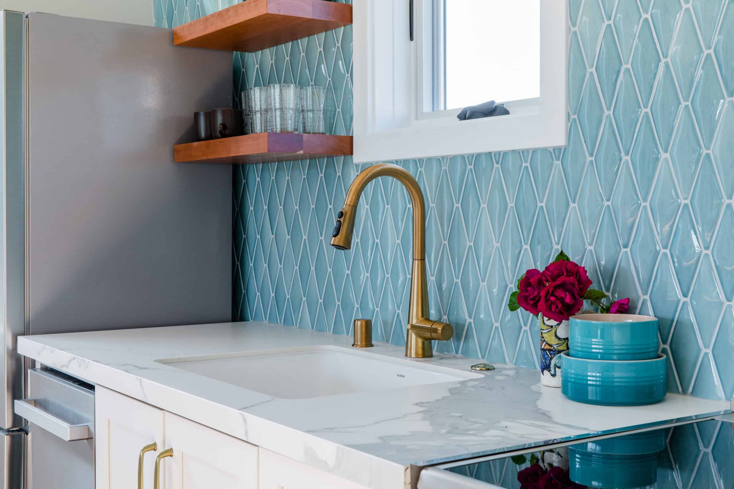 Modern kitchen with blue tile backsplash and gold fixtures.
