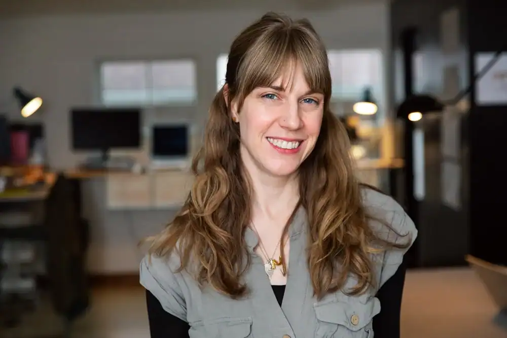 Smiling woman in office environment representing Office of Ordinary Architecture.
