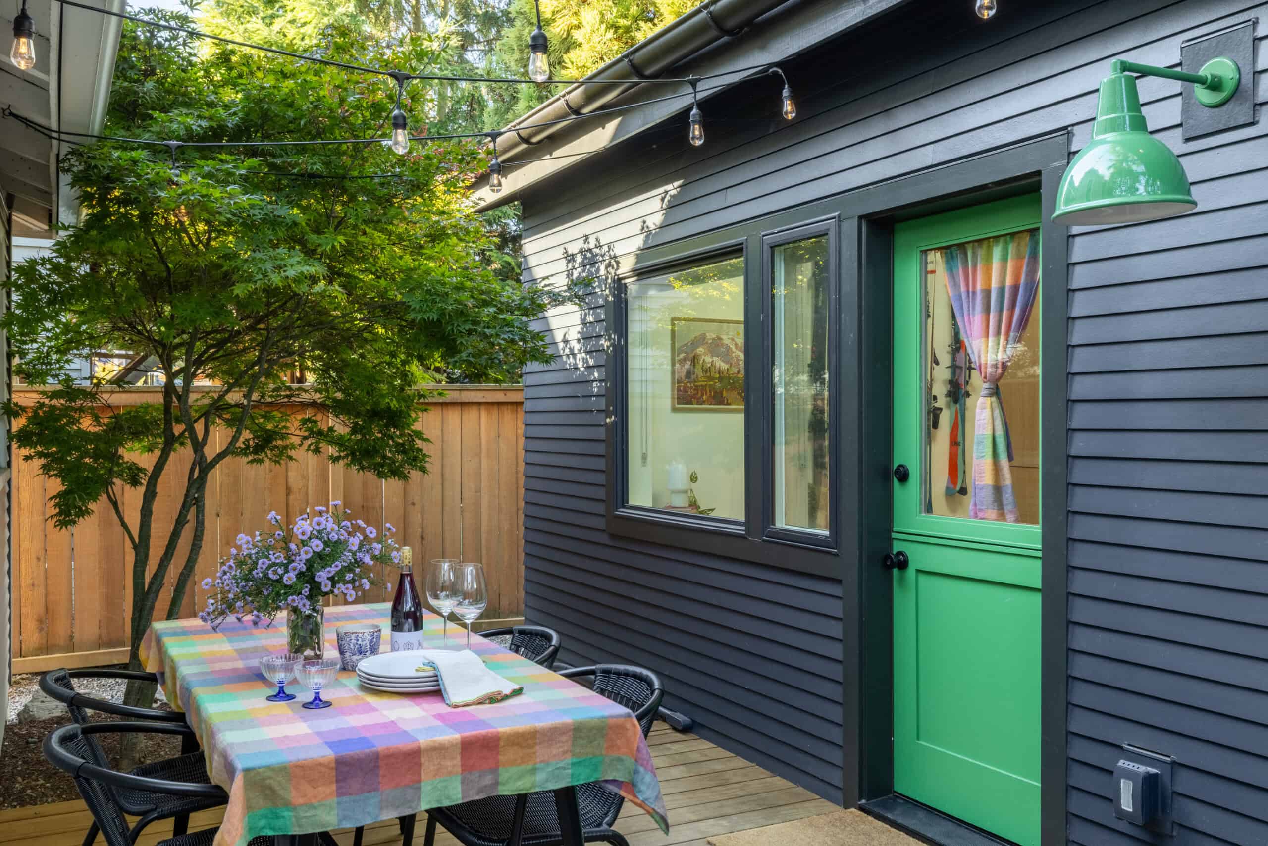 Colorful backyard studio with green door and outdoor dining area in Seattle.