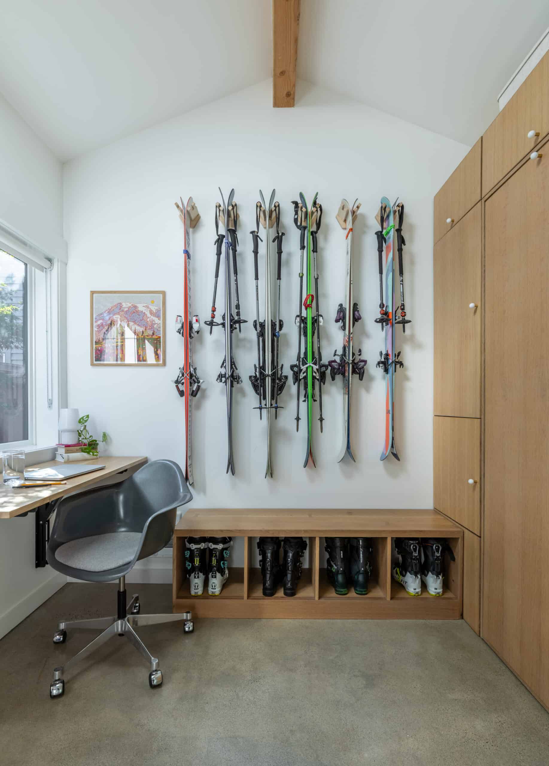 Ski storage wall with skis and boots in a modern home office.