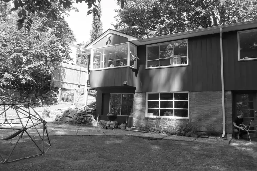Modern residential house with large windows and outdoor garden area.
