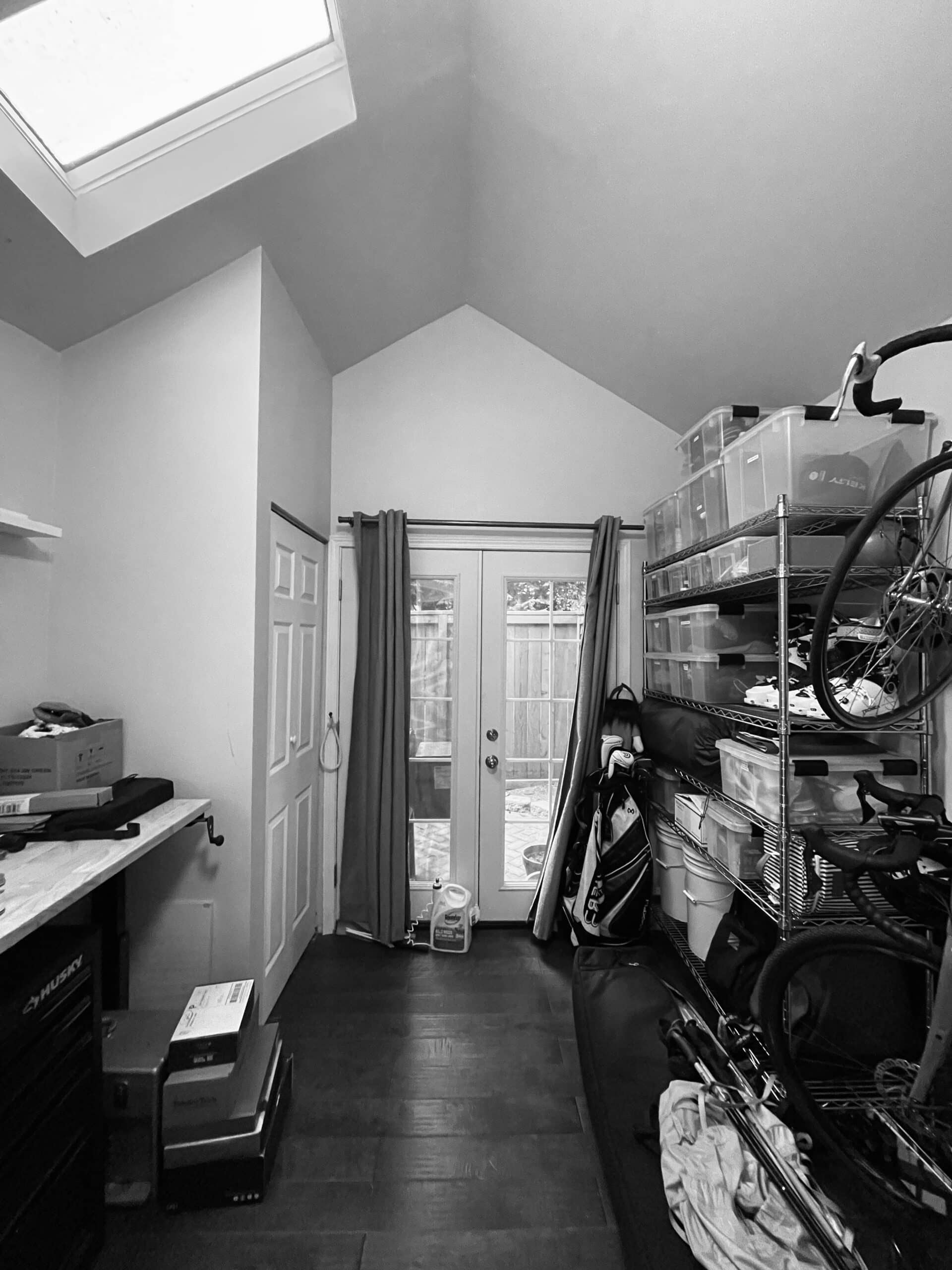 Interior view of a small, organized office space with storage shelves and a door to the backyard.