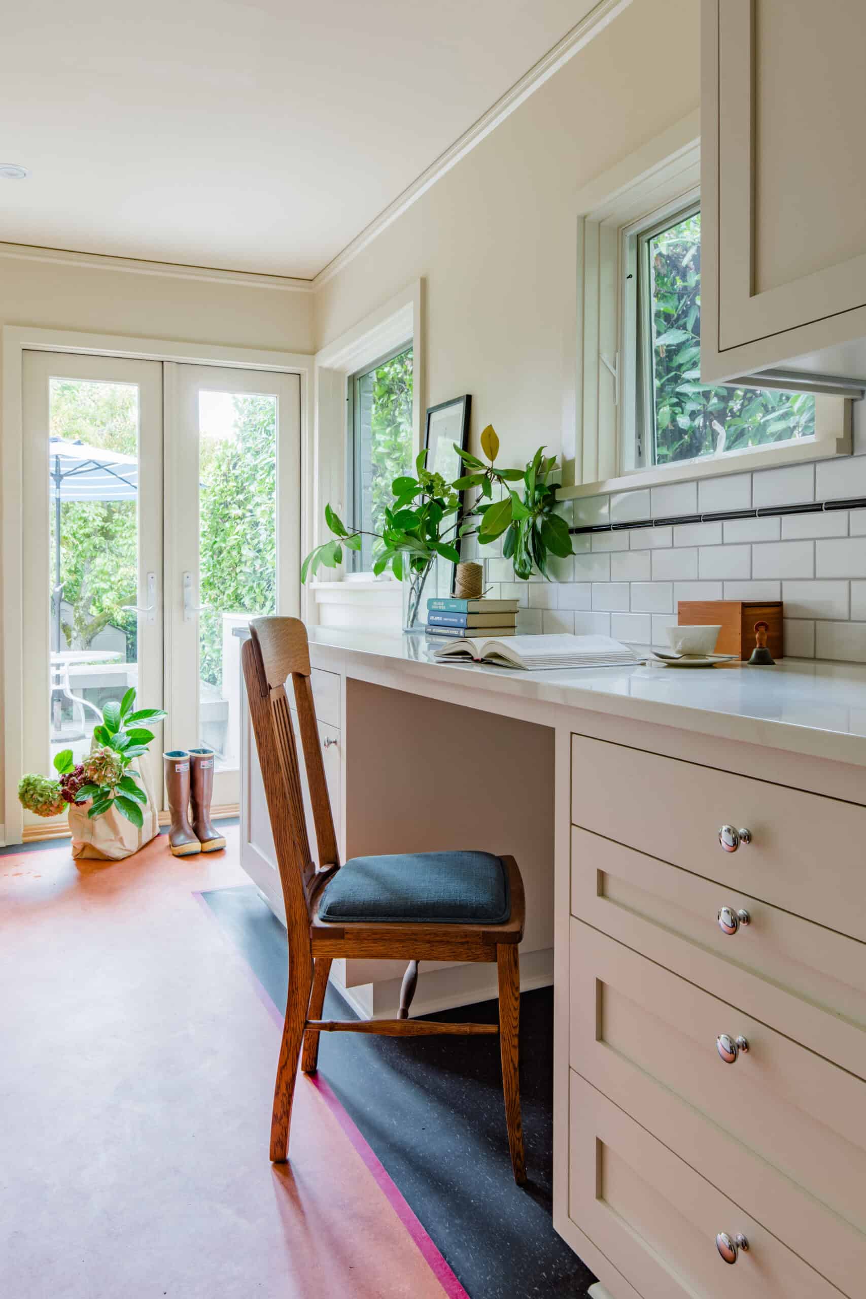 Bright vintage-inspired kitchen with white cabinetry and large windows.