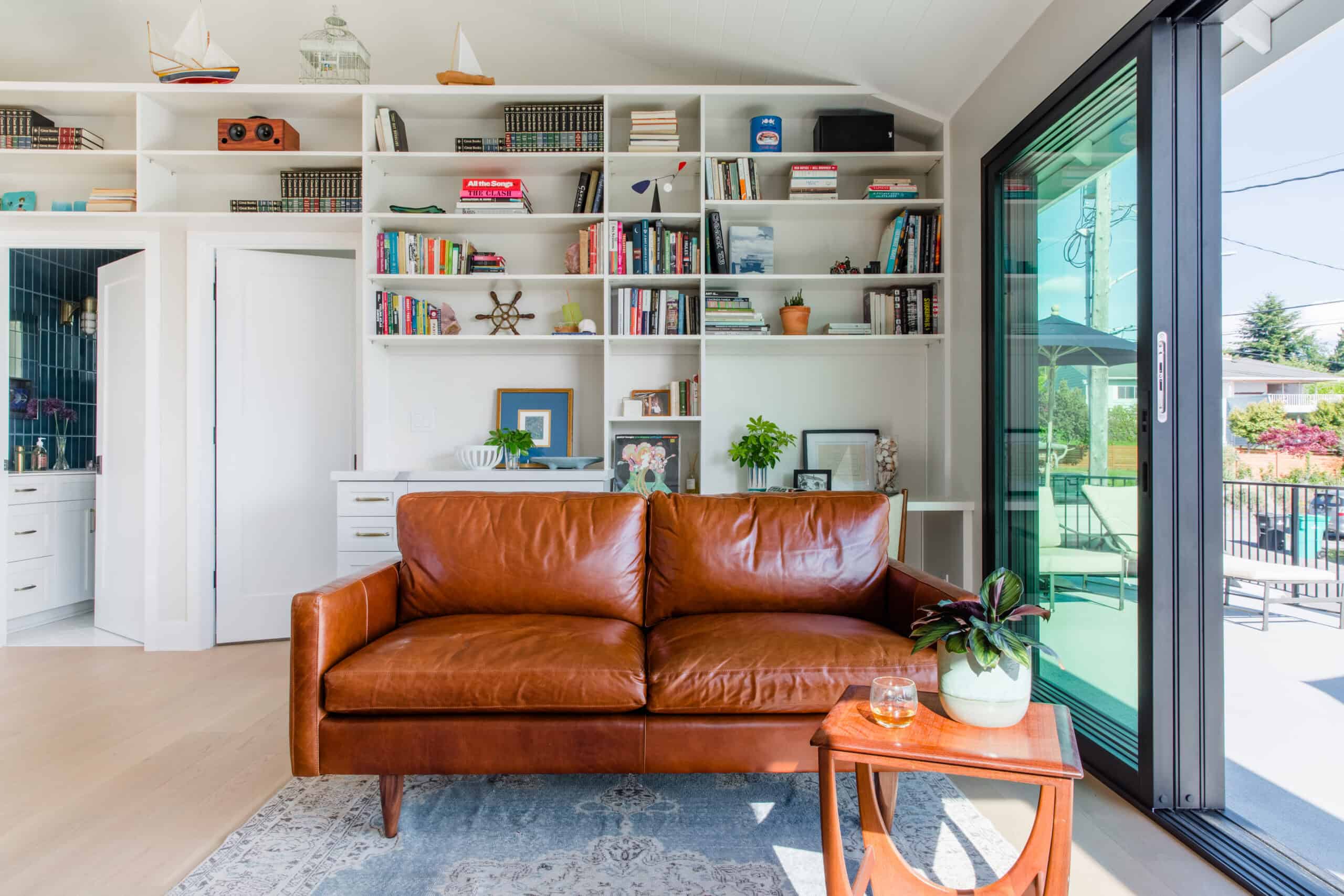 Modern living room with white built-in shelves and a brown leather sofa.