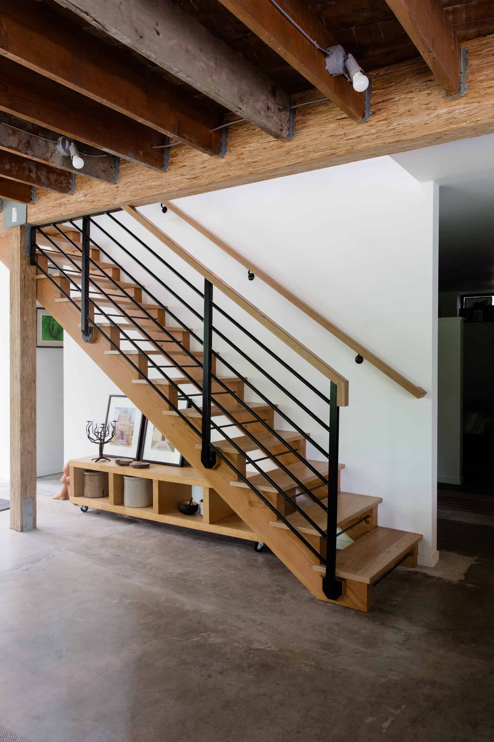 Interior staircase with wooden steps and black metal railing in modern home.