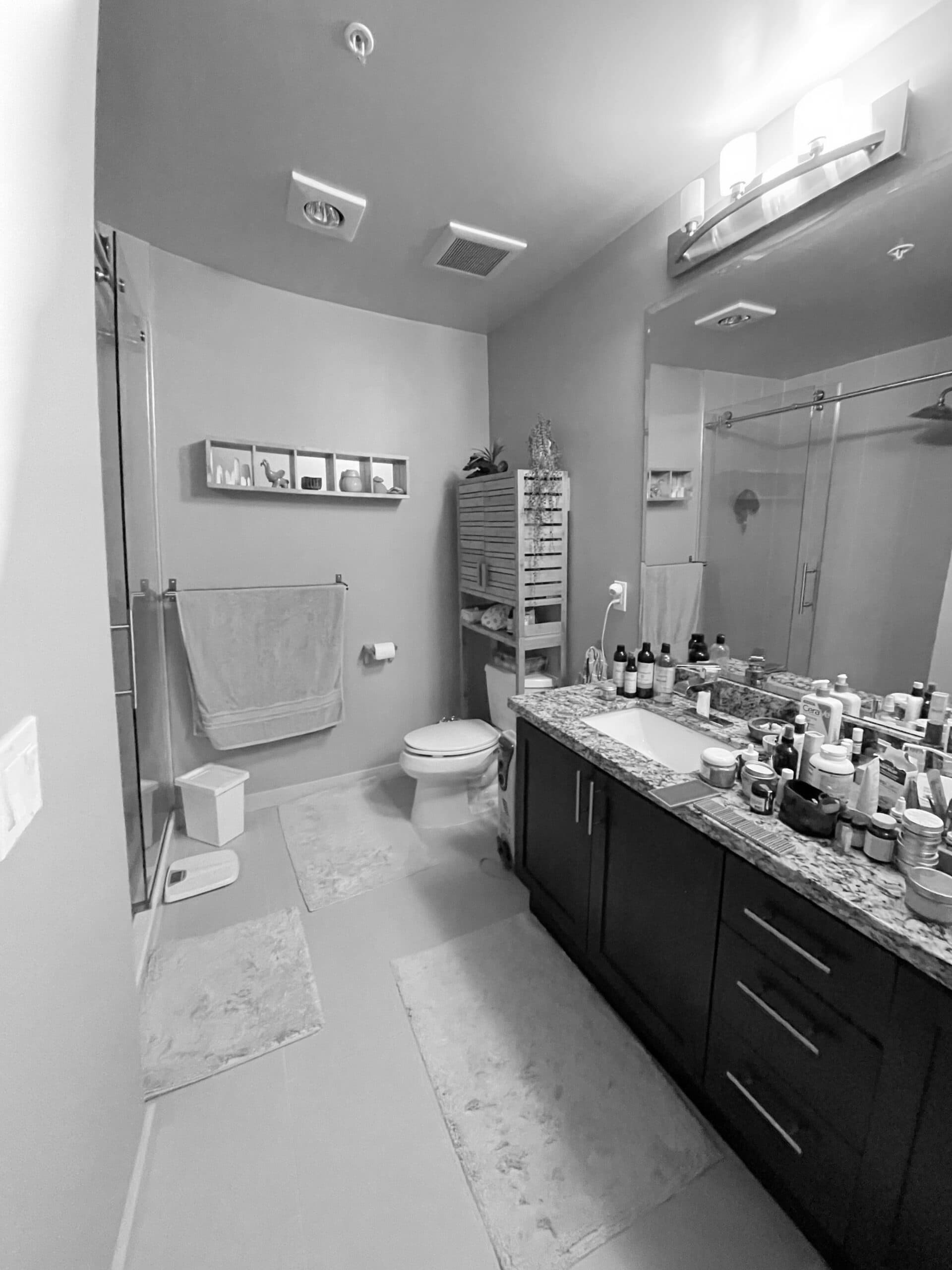 Modern condo bathroom with vanity, mirror, and toiletries in black and white.