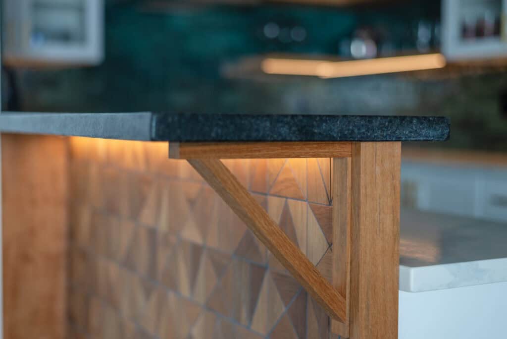 Close-up of modern interior with geometric wood paneling and black countertop.