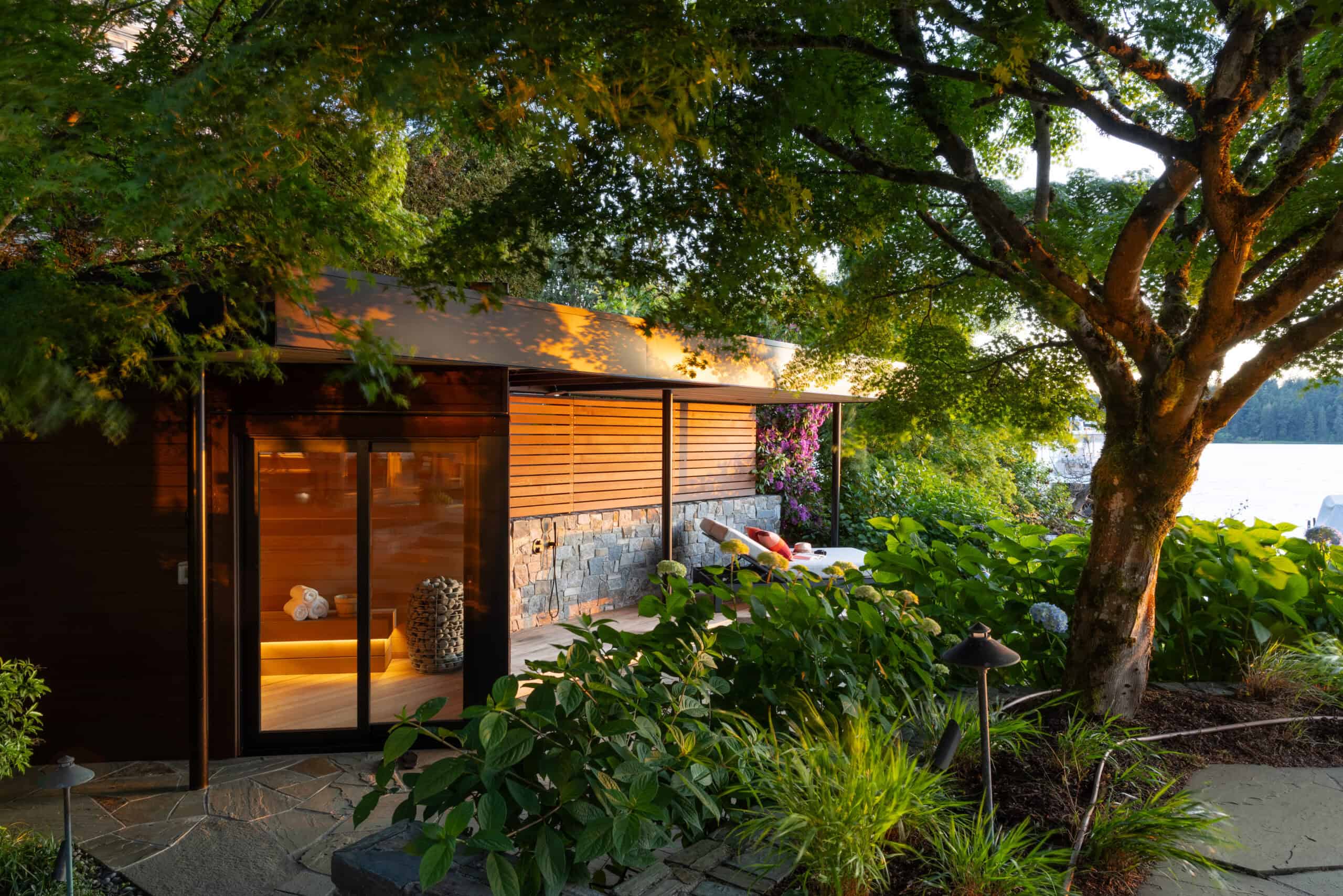 Modern lakeside retreat with large glass doors and lush garden surroundings.