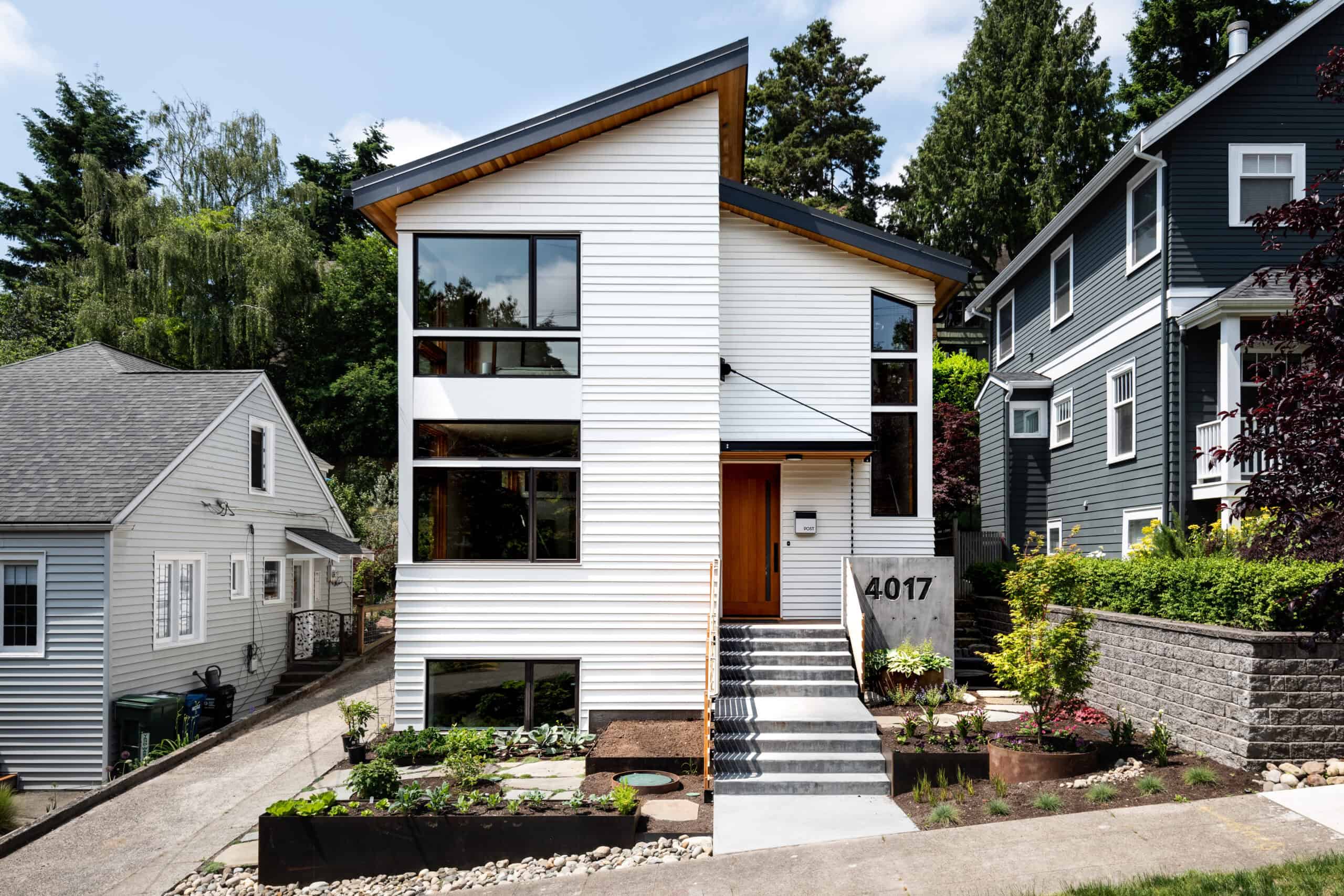 Modern white residential home with large windows and landscaped front yard.