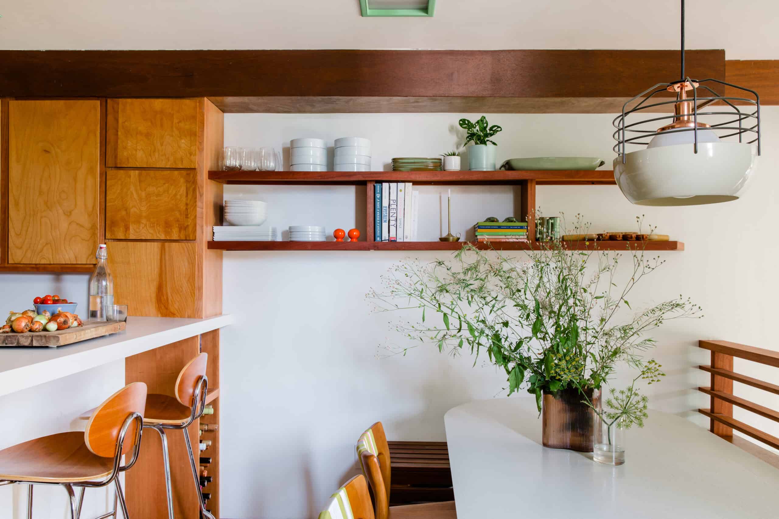 Modern kitchen with wooden cabinets, open shelves, and a large green plant.