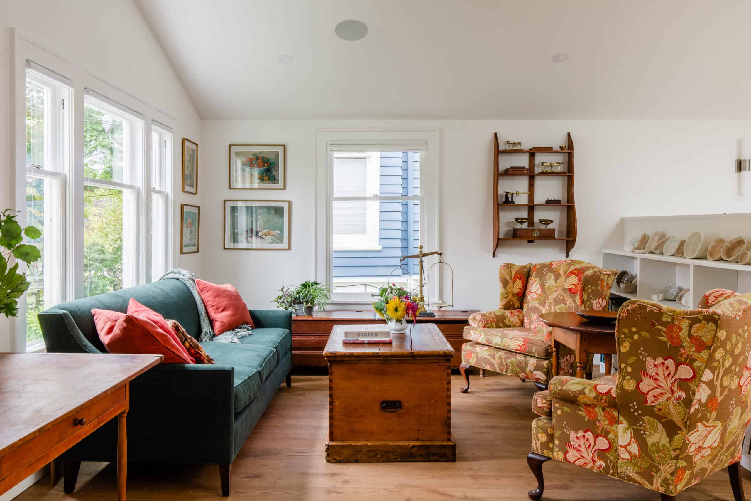 Bright living room with vintage furniture and large windows in a cozy cottage.