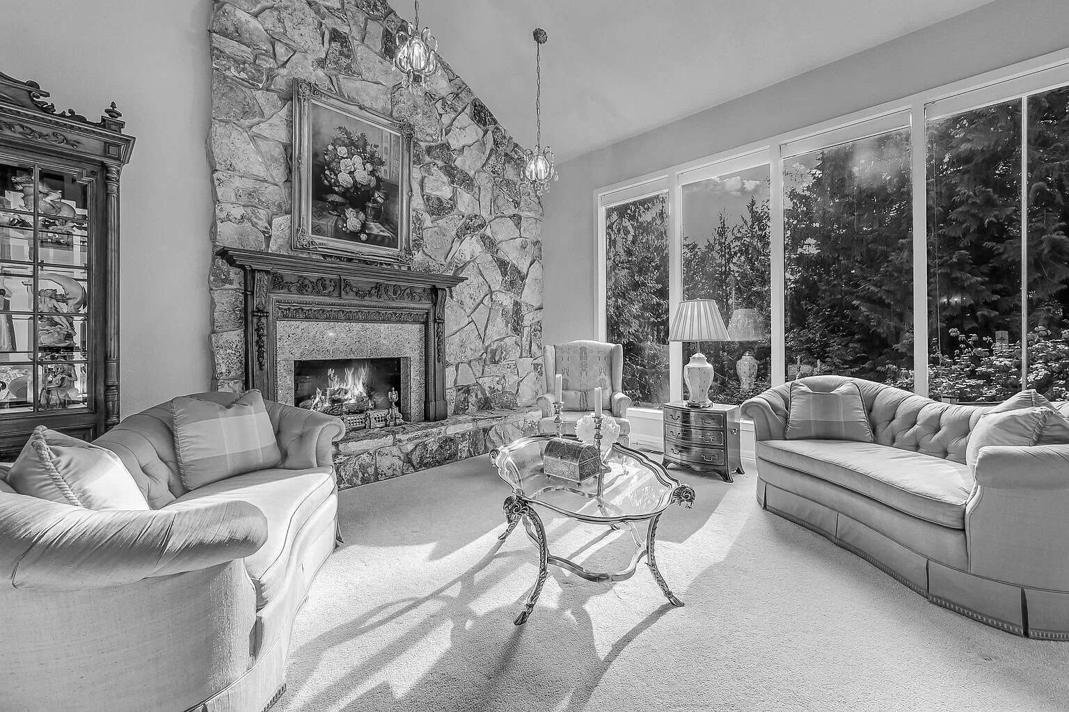 Cozy living room with stone fireplace and large windows in a modern home.