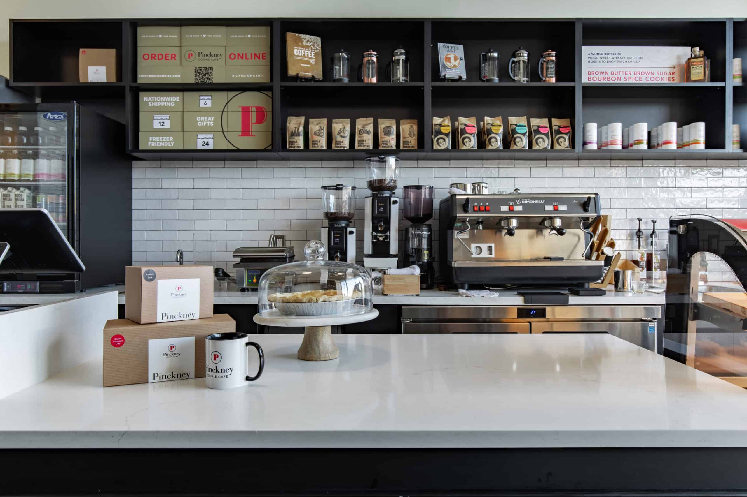 Modern cafe counter with coffee equipment and baked goods display.