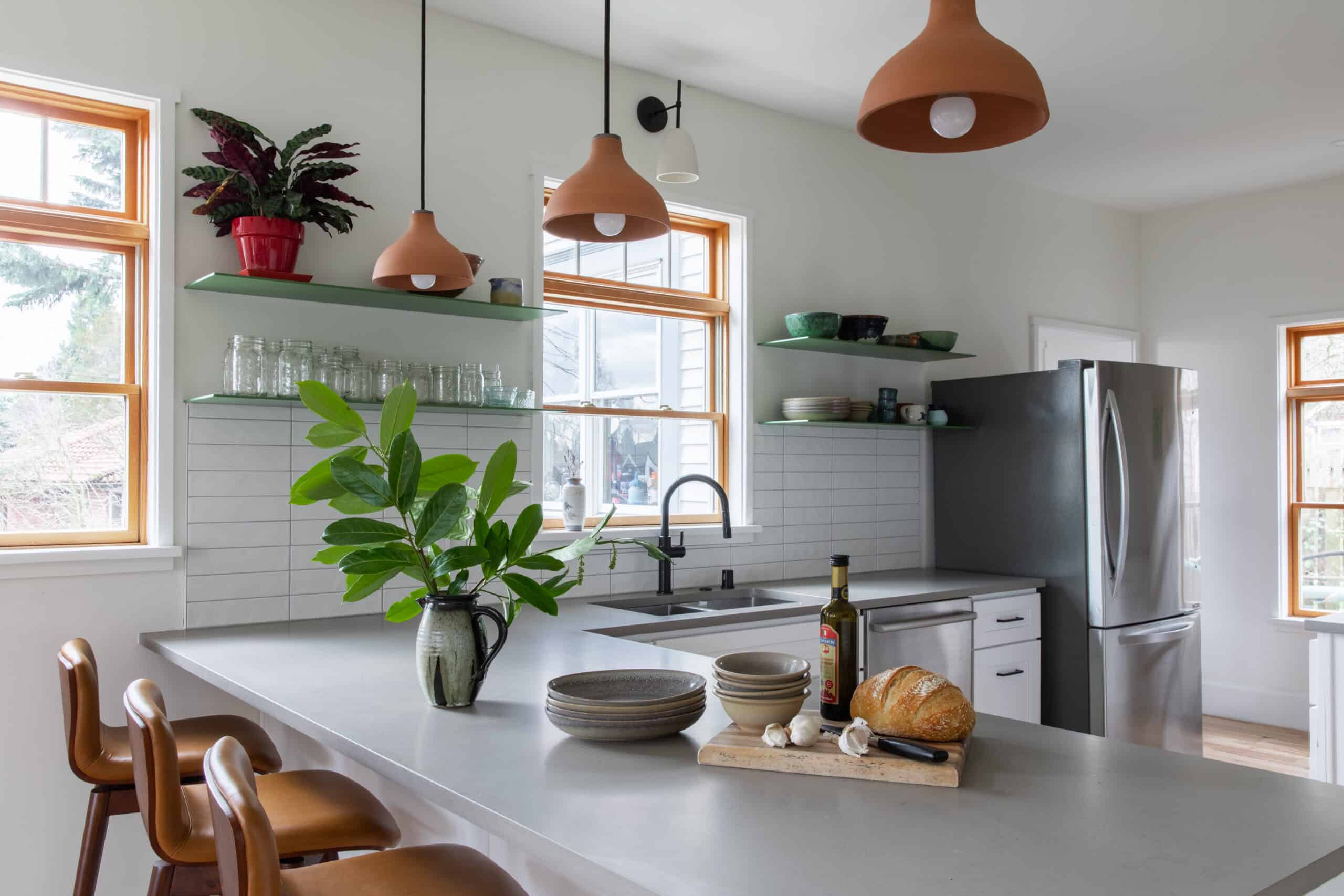 Bright modern kitchen with white cabinets, wooden accents, and green decor.