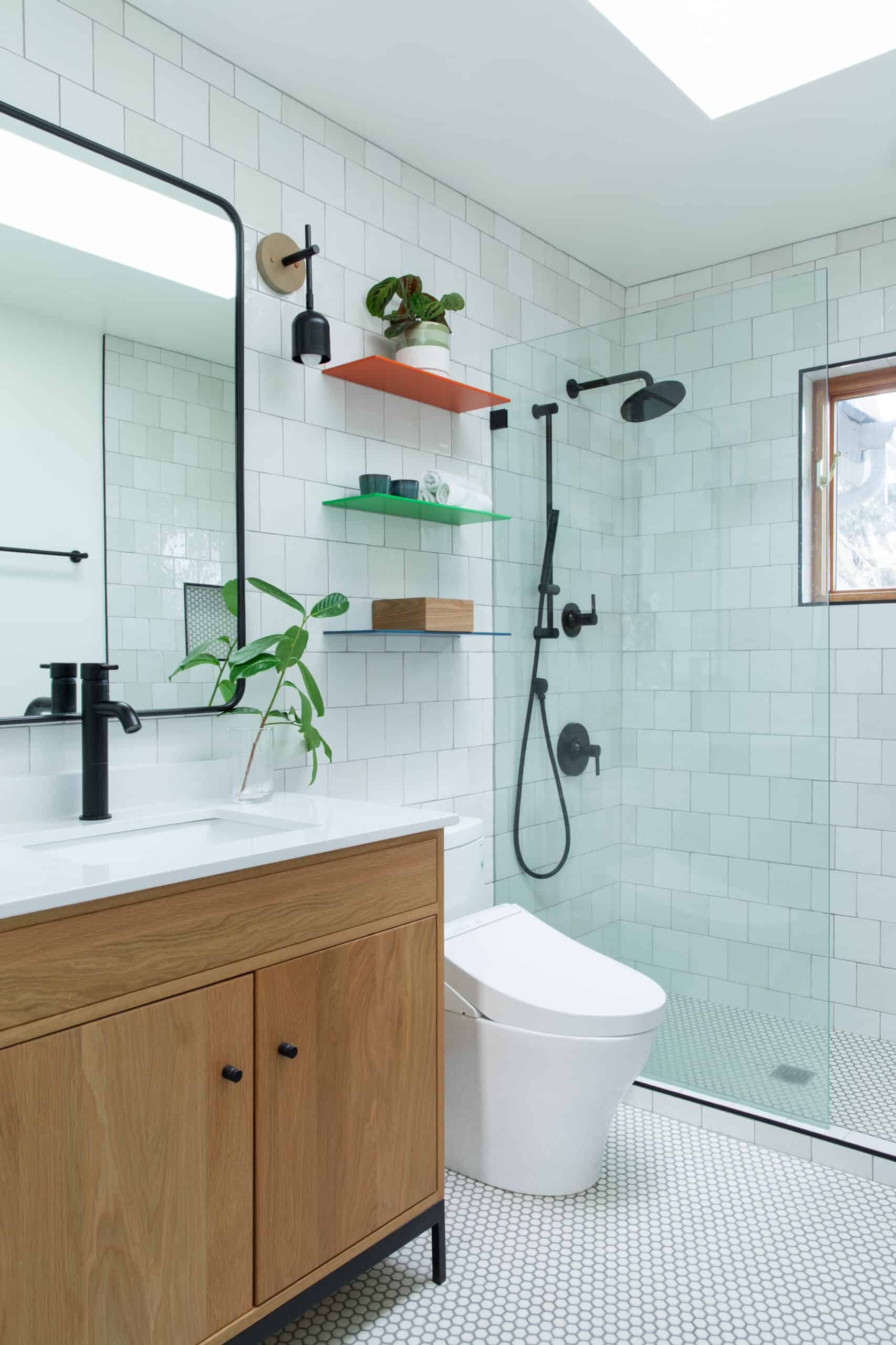 Contemporary bathroom with white tiles, wooden vanity, and black fixtures.