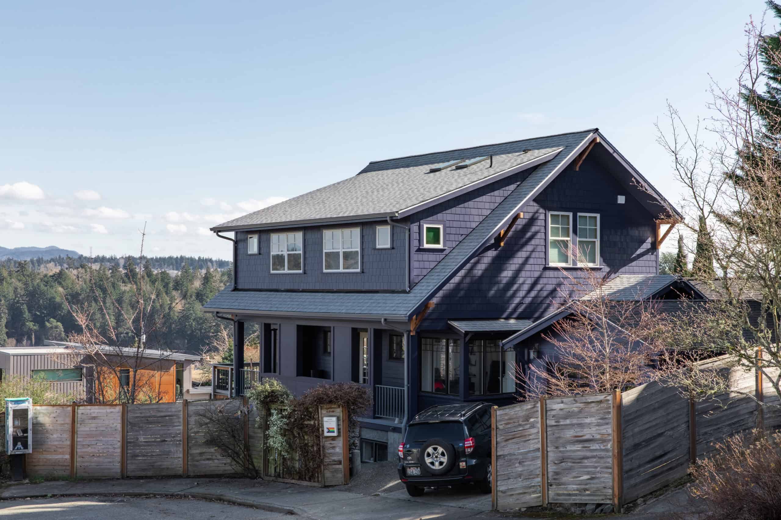 Modern two-story house with dark blue exterior and large windows.