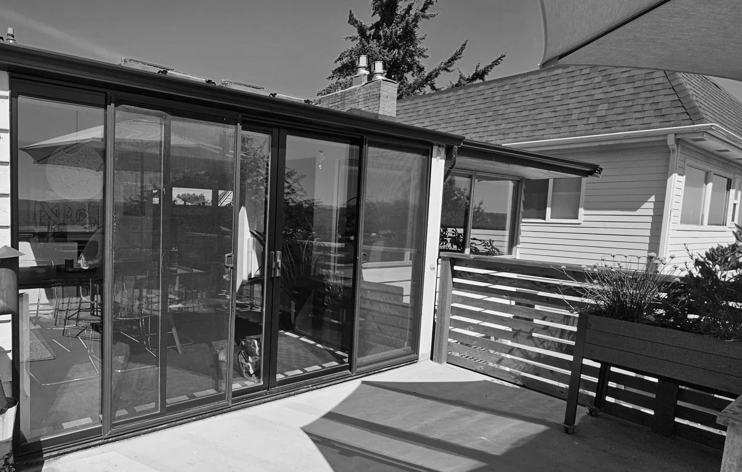 Modern glass sunroom extension with outdoor seating and deck area.