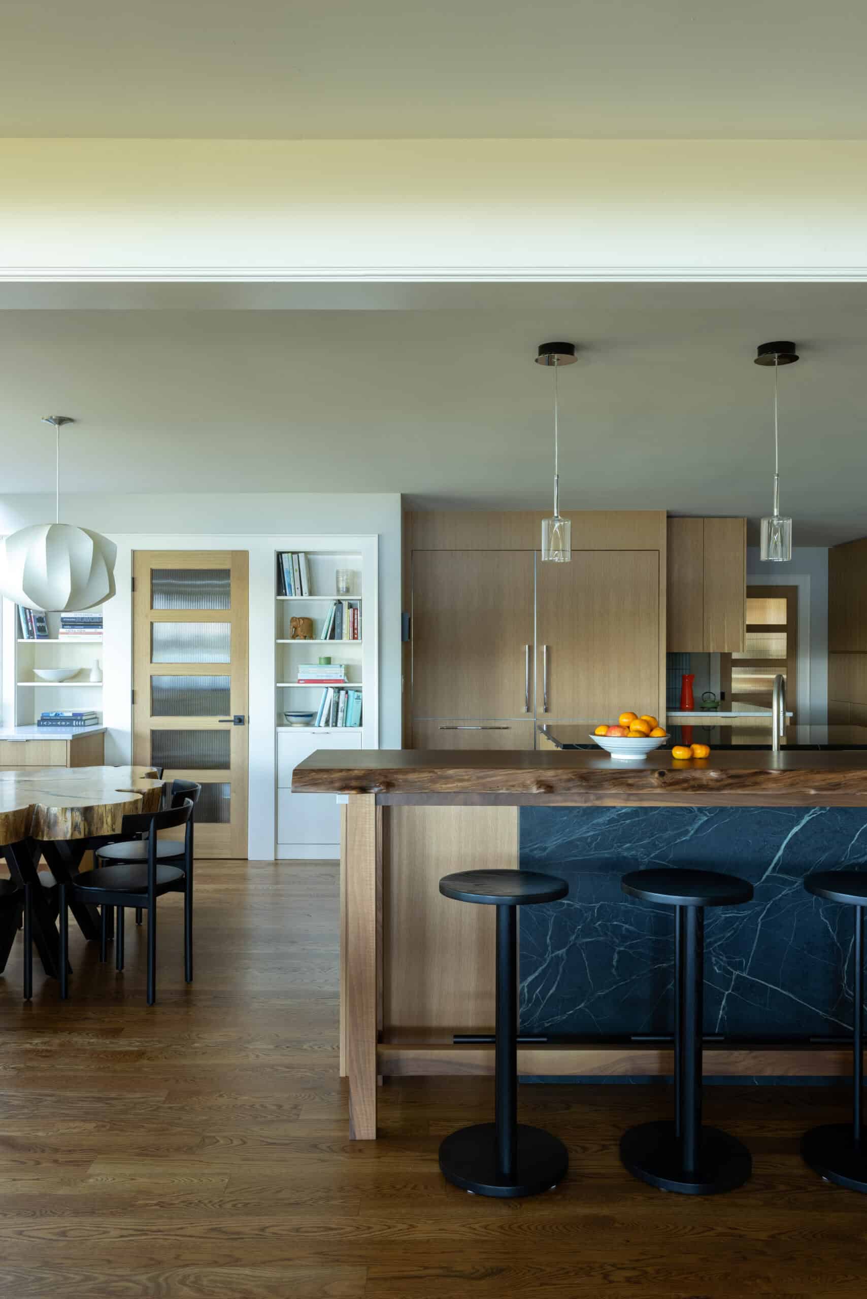 Contemporary kitchen with wooden cabinets and island, bar stools, and open shelving.