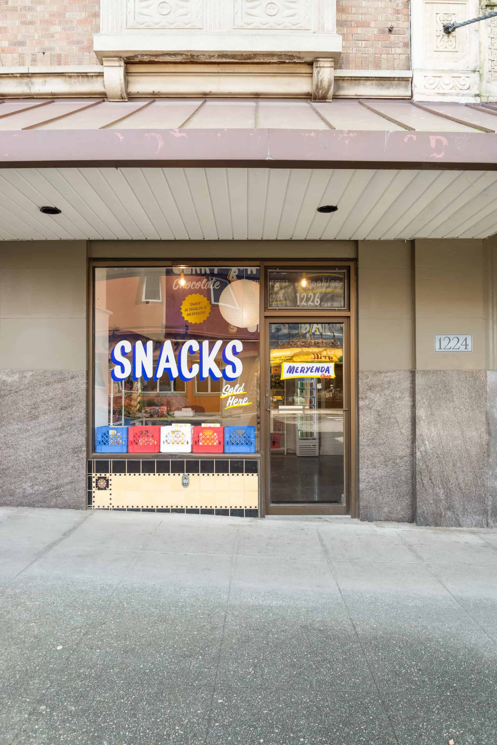 Snack shop storefront with large SNACKS sign and colorful window display.