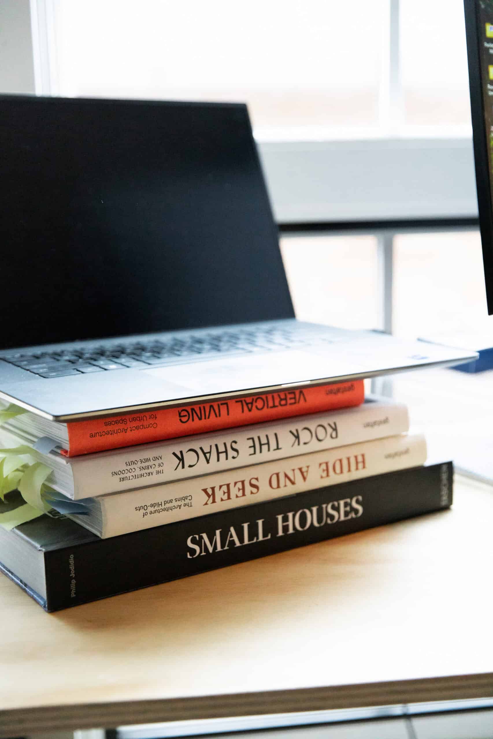 Modern workspace with laptop and architecture books on a wooden desk.