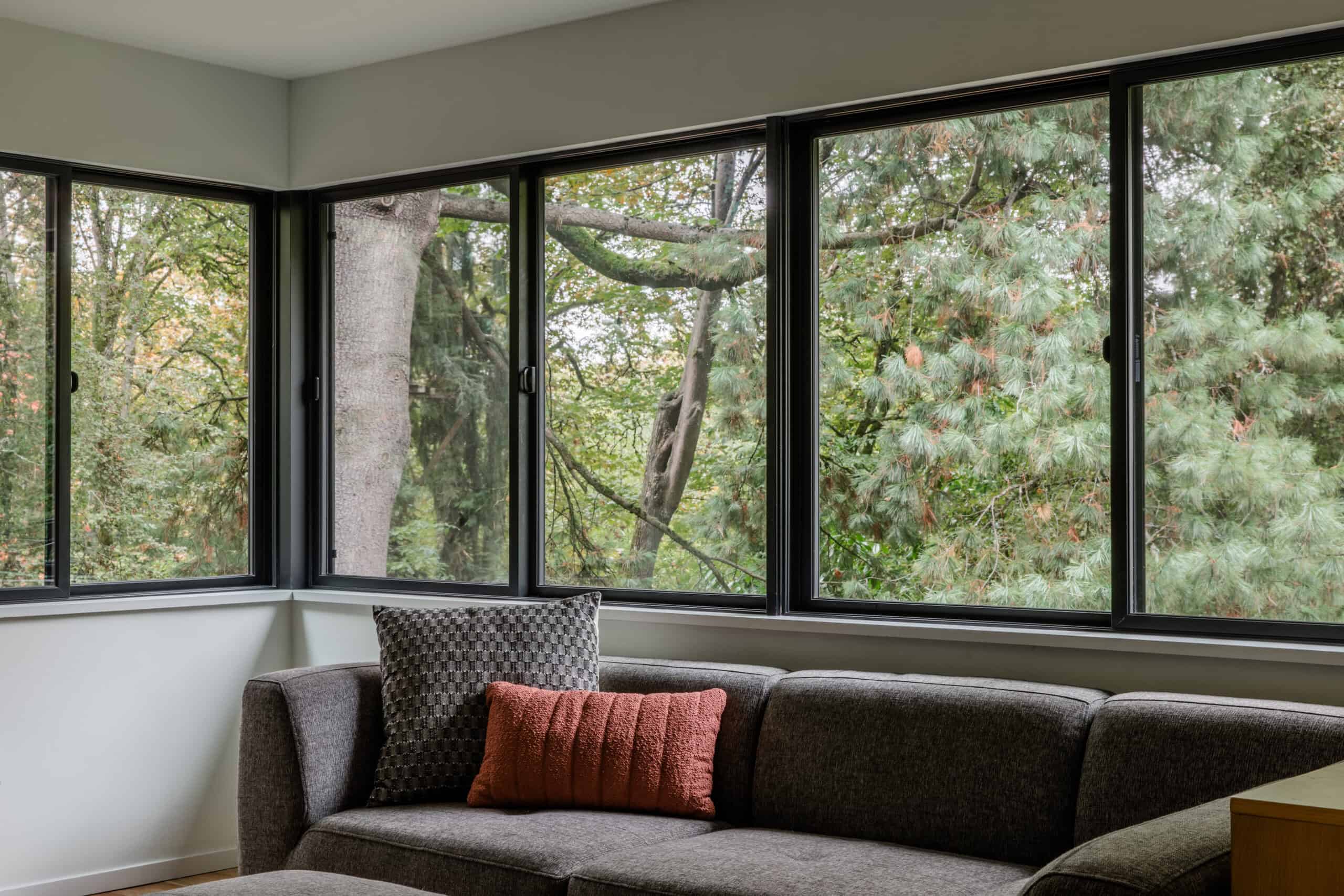Living room with expansive windows overlooking trees and nature.